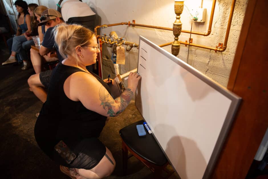 Employee writing competition bracket on whiteboard for latte art throwdown.