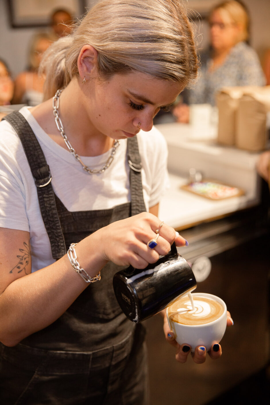 Barista pouring latte art in a mug.