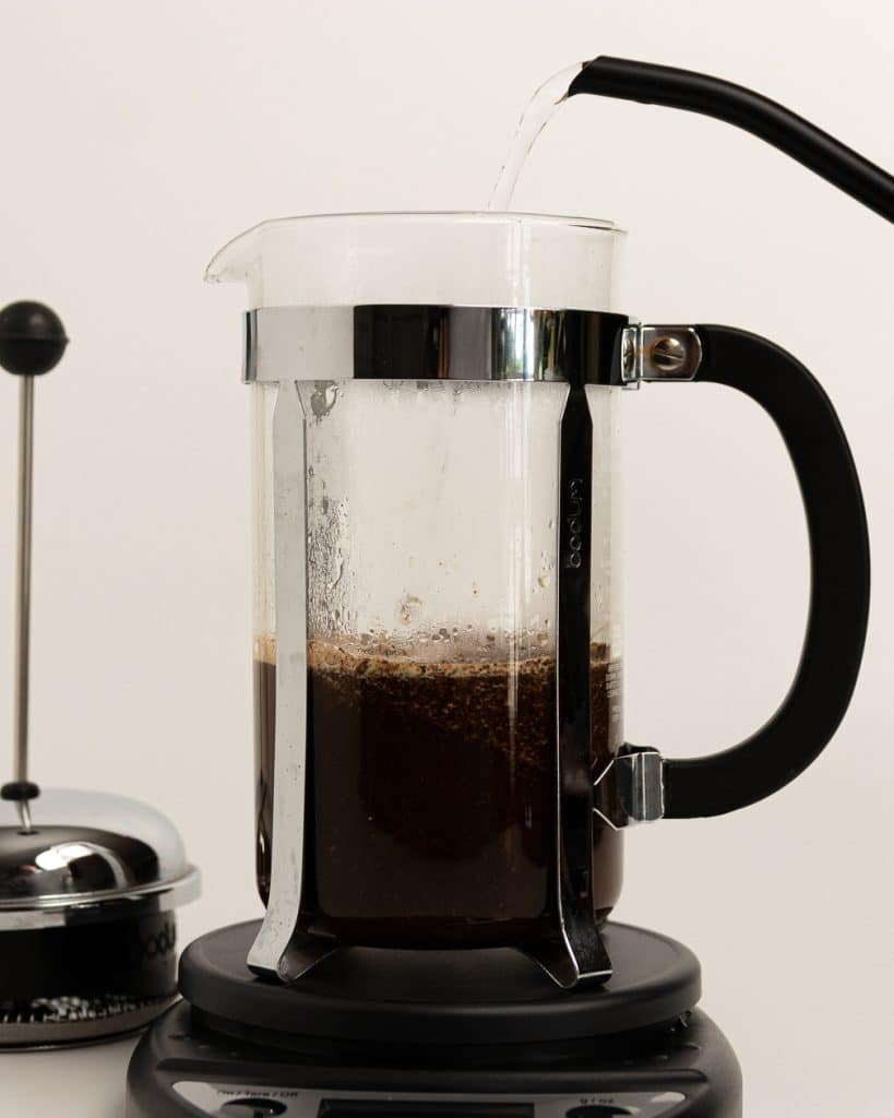 hot water being poured over grounds in a French press base 