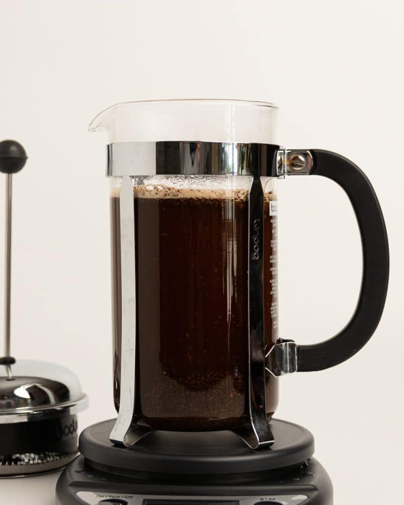 hot water being poured over grounds in a French press base 