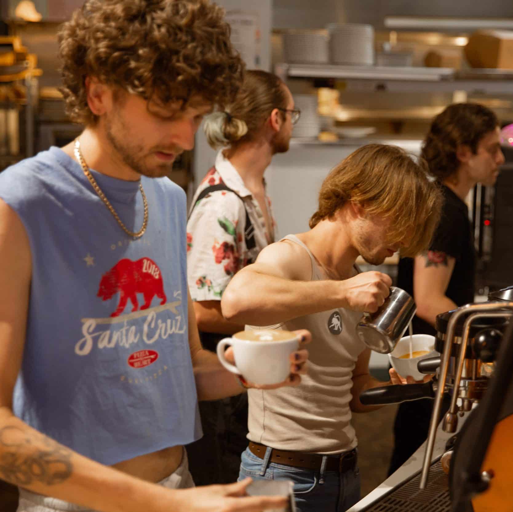 Two baristas pouring latte art.